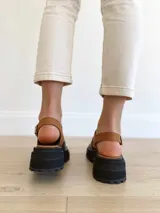 Sandalias de cuero color negro y camel, con plataforma track y hebilla ajustable.