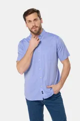 Camisa sport lisa de manga corta en color celeste, con cuello abotonado, cierre frontal con botones, bolsillo en el pecho y etiqueta decorativa en el ruedo.
