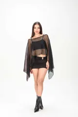 Poncho negro de tejido traslúcido con brillo sutil, mangas amplias y caída asimétrica.