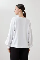 Sweatshirt blanco de manga larga con cuello redondo y puños elásticos.