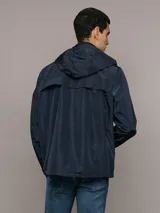 Campera ligera Calvin Klein de corte regular, confeccionada en tejido técnico resistente al viento. Presenta capucha con cordones ajustables, cierre frontal con cremallera, bolsillos laterales con cierre y puños elásticos.