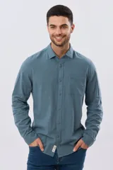 Camisa de lino de manga larga en color beige, con cuello camisero, cierre frontal de botones y un bolsillo ojal en el pecho.