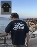 Remera negra de corte oversize con estampado gráfico en la espalda con la inscripción 'New York' en blanco y detalles en rojo, y diseño frontal minimalista.