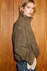 Chaqueta de ante con cuello subido, manga larga y bajo abullonado con elástico. Presenta cierre frontal con cremallera y botones a presión ocultos, además de bolsillos laterales de vivo.