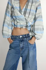 Jeans de tiro medio con diseño barrel, cinco bolsillos y cinturón fino del mismo tejido. Presenta pernera ancha en los muslos que se estrecha gradualmente hacia el tobillo, con cierre frontal de cremallera y botón.