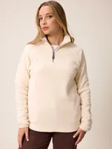 Sweater de polar con medio cierre frontal, cuello alto y mangas largas. Presenta un diseño liso en color crema con un pequeño bordado en el pecho.