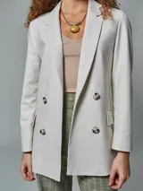 Blazer recto color crudo, de lino, con solapas de muesca, cierre cruzado con doble botonadura, mangas largas y bolsillos con solapa.