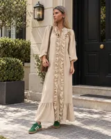 Vestido largo de estilo camisero color beige, con mangas abullonadas y volados frontales a lo largo de la botonadura.