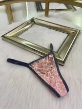 Pack de tres microtangas de encaje con diseño floral, cuentan con tiras laterales regulables y bordes con terminación en cinta elástica. El set incluye una prenda negra, una blanca con estampado floral negro y una beige con estampado floral negro.