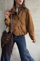 Campera tipo bomber de gamuza color camel, con diseño de doble botonadura frontal, cuello camisero y mangas largas con puños abotonados.