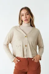 Cardigan de tejido de punto color gris melange, con escote en V, cierre frontal con botones y bolsillos tipo cartera. Presenta un diseño de corte recto y mangas largas.