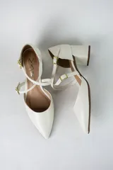 Sandalia de tacón cuadrado color blanco, con diseño de punta fina cerrada y tiras cruzadas ajustables con hebillas metálicas doradas.