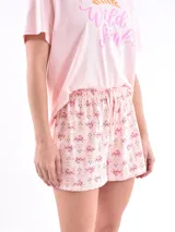 Conjunto de pijama compuesto por una remera de manga corta color rosa con estampa frontal y un short estampado con diseño pequeño y repetitivo.