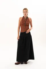 Pollera larga de color negro, con corte a la cadera y falda con frunce que aporta volumen y movimiento. Confeccionada en tela suave con acabado tipo piel de durazno.