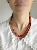Collar corto compuesto por cuentas esféricas de piedra ágata en tonos naranjas y rojizos, con cierre metálico dorado.