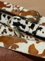 Cinto de cuero vacuno con pelo natural, con diseño de manchas tipo animal print. Cuenta con hebilla metálica y costuras reforzadas.