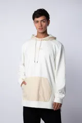 Buzo tipo canguro con capucha, confeccionado en una combinación de algodón rústico y microfibra. Presenta un diseño bicolor en blanco y beige, con bolsillo frontal tipo canguro en contraste, cordones ajustables en la capucha y estampado personalizado en el frente.