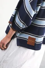 Remera rosa con rayas horizontales azul marino y bordó, cuello tipo polo marrón con botones y mangas cortas amplias.