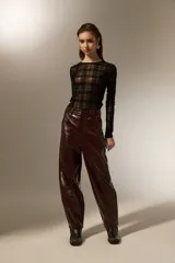 Pantalon de eco-cuero con diseño barrel, de tiro alto y corte holgado. Cuenta con bolsillos laterales y cierre frontal con botón.