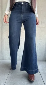 Jean de corte oxford con tiro alto, confeccionado en denim azul oscuro con costuras a tono. Presenta un diseño de pierna ancha y cierre frontal con botón metálico.