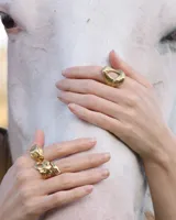 Anillo plateado con forma orgánica irregular y un agujero en el centro.