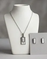 Set de joyería compuesto por un collar con dije rectangular y un par de aros a juego, ambos con incrustaciones de nácar y estructura de acero inoxidable.