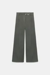 Pantalón gris de tiro alto con bolsillos delanteros y traseros. Detalle de pinzas delanteras. Cierre frontal con cremallera, botón interior y botones decorativos.