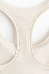 Top deportivo color beige con espalda nadadora, escote redondo y banda elástica inferior.