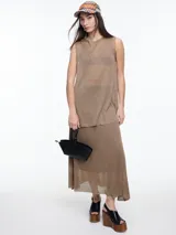 Musculosa de tejido fino y translúcido con sutil brillo metálico, de corte relajado, sin mangas y largo por debajo de la cadera con aberturas laterales.