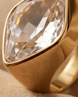 Anillo de bronce bañado en oro, de diseño ancho y moderno, con un gran cristal de Swarovski facetado en forma de rombo invertido.