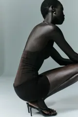 Body entallado de poliamida color marrón, con escote profundo y cuello metálico tipo choker integrado. Presenta un diseño sin mangas con frunces en el busto.