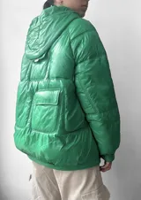 Campera puffer verde con capucha, cierre frontal con cremallera y bolsillos con solapa.