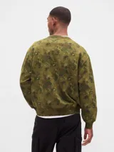 Buzo de cuello redondo, manga larga y calce holgado, color verde militar con estampado floral camuflado. Presenta el logo "GAP" bordado en el pecho en color blanco.
