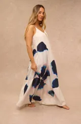 Vestido largo color blanco con diseño estampado floral de gran tamaño en tonos azules y rosados, tirantes finos y escote en V.