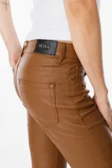 Pantalón de ecocuero color marrón, de corte recto con terminación ligeramente acampanada y tajos frontales en el ruedo. Cuenta con cierre y botón frontal, además de bolsillos laterales y traseros.