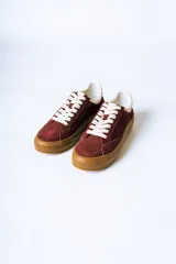 Championes urbanos de gamuza color bordó con suela de goma color caramelo y cordones blancos.