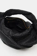 Bolso de mano negro con cuerpo cubierto de apliques brillantes, diseño estructurado con asa superior integrada y cierre principal. Incluye bolsillo interior con cremallera y cadena para usar como bandolera.