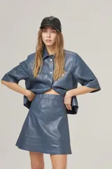 Minifalda de cuero azul con cintura alta, corte en línea A, cierre metálico lateral y bolsillos traseros.