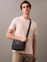 Bolso bandolera Calvin Klein Jeans color negro con logo estampado en blanco.