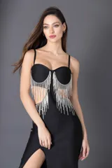 Vestido midi negro con escote corazón, breteles finos y falda ajustada con tajo lateral. Presenta apliques de flecos de strass en el busto y recortes laterales.