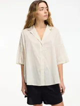 Camisa de algodón con cuello solapa, cierre frontal de botones y mangas tres cuartos de corte holgado.