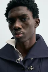 Sudadera de calce relajado color azul marino, con cuello alto y cierre frontal mediante alamares metálicos. Presenta manga larga y terminaciones en rib en puños y cintura.