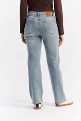 Jean de corte recto y tiro medio, confeccionado en denim de tono azul claro con acabado lavado. Presenta cierre frontal con botón y cremallera, además de bolsillos laterales y traseros.