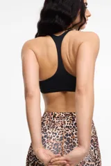 Top deportivo negro con escote en V y tirantes anchos que se cruzan en la espalda. Incluye copas removibles.