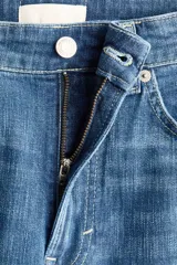 Jean de cinco bolsillos en denim de algodón con stretch. Modelo bootcut de tiro alto, ajustado de cintura a cadera y con corte ligeramente acampanado desde la rodilla hacia el bajo. Presenta raya marcada en la parte delantera y trasera.