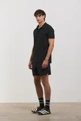 Chomba deportiva de manga corta, color negro, con cuello polo y cierre frontal de tres botones. Confeccionada en tejido técnico ultra liviano, fresco y respirable con alta elasticidad.