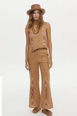 Pantalón camel de lino, de corte recto y tiro alto, con detalles bordados en la parte inferior de las piernas.