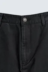 Pantalón de corte carrot fit confeccionado en tejido de algodón con estructura diagonal y efecto lavado. Presenta bolsillos frontales con bolsillo cerillero, bolsillos traseros de plastrón y cierre frontal con cremallera y botón.
