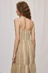 Vestido largo negro de algodón, con breteles finos, escote con frunce y lazo regulable. Tiene cintura definida y falda amplia escalonada, con detalles bordados verticales en contraste.