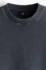 Remera de algodón con efecto lavado, color gris oscuro, corte regular fit, mangas cortas, hombros caídos, cuello redondo acanalado y bajo sin rematar.